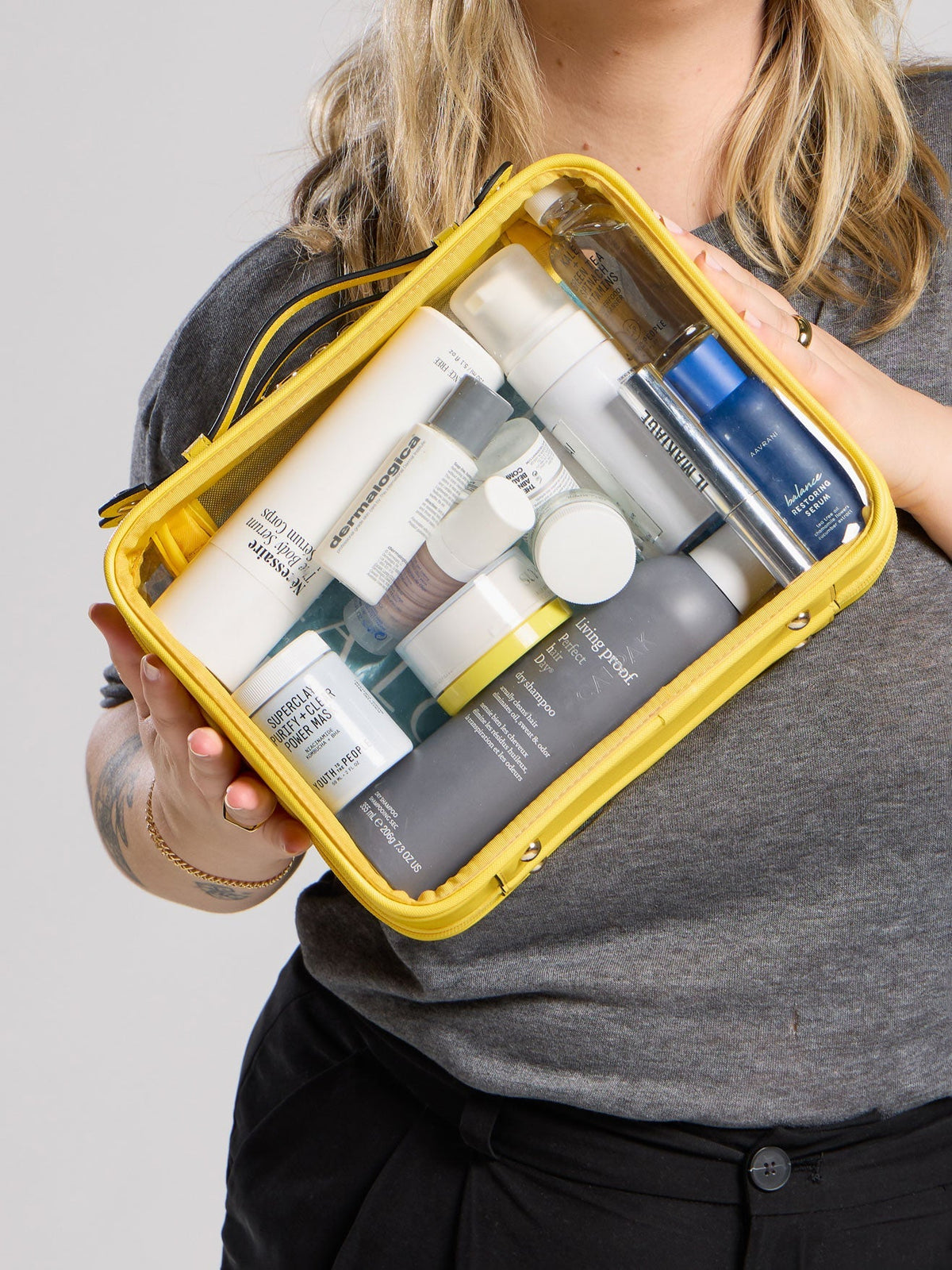 Model displaying fully packed Large Clear Cosmetic Case perfect for skin care items; CCC2001-LEMON