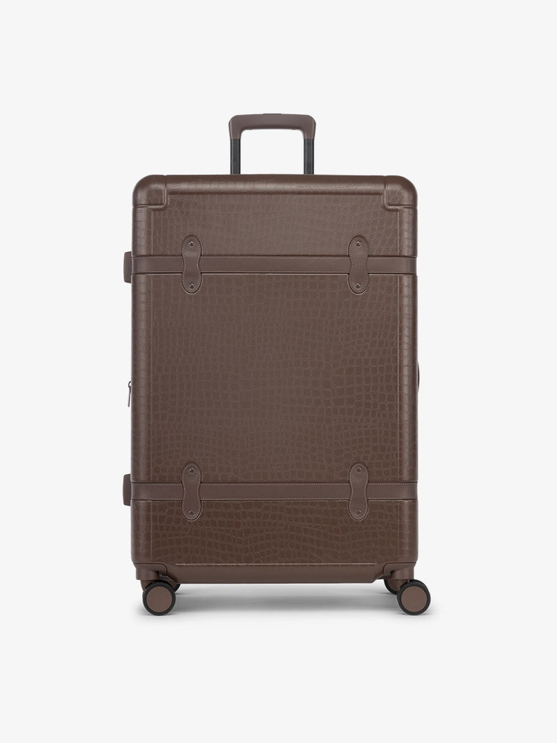 CALPAK TRNK large suitcase with hard shell exterior and four 360 spinner wheels in espresso vintage trunk style