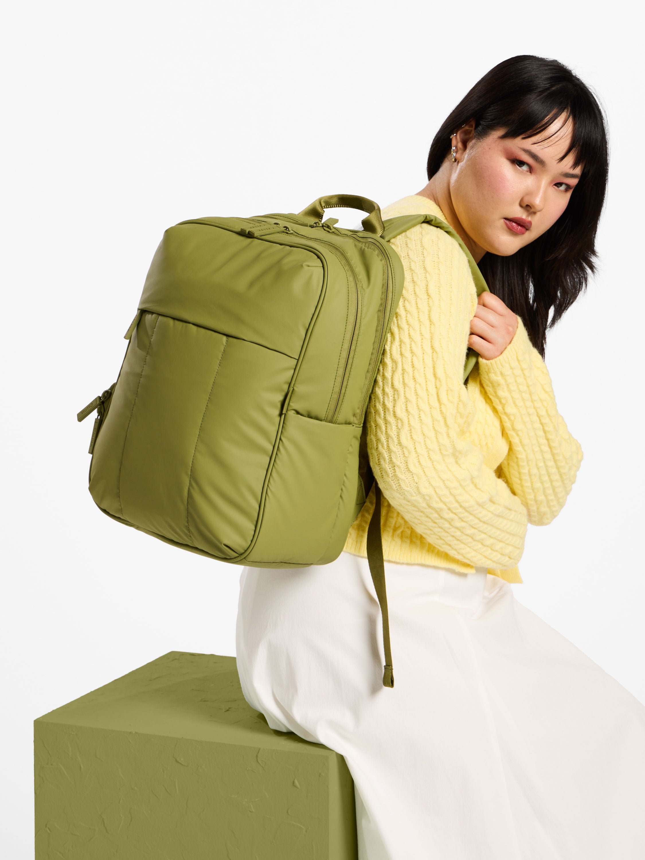 Model wearing green CALPAK luka laptop backpack for 15 inch laptop over shoulder