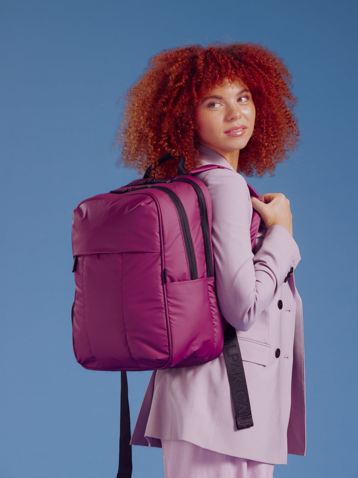 Model wearing CALPAK 15 inch Laptop Backpack on back in purple plum; BPL2001-PLUM