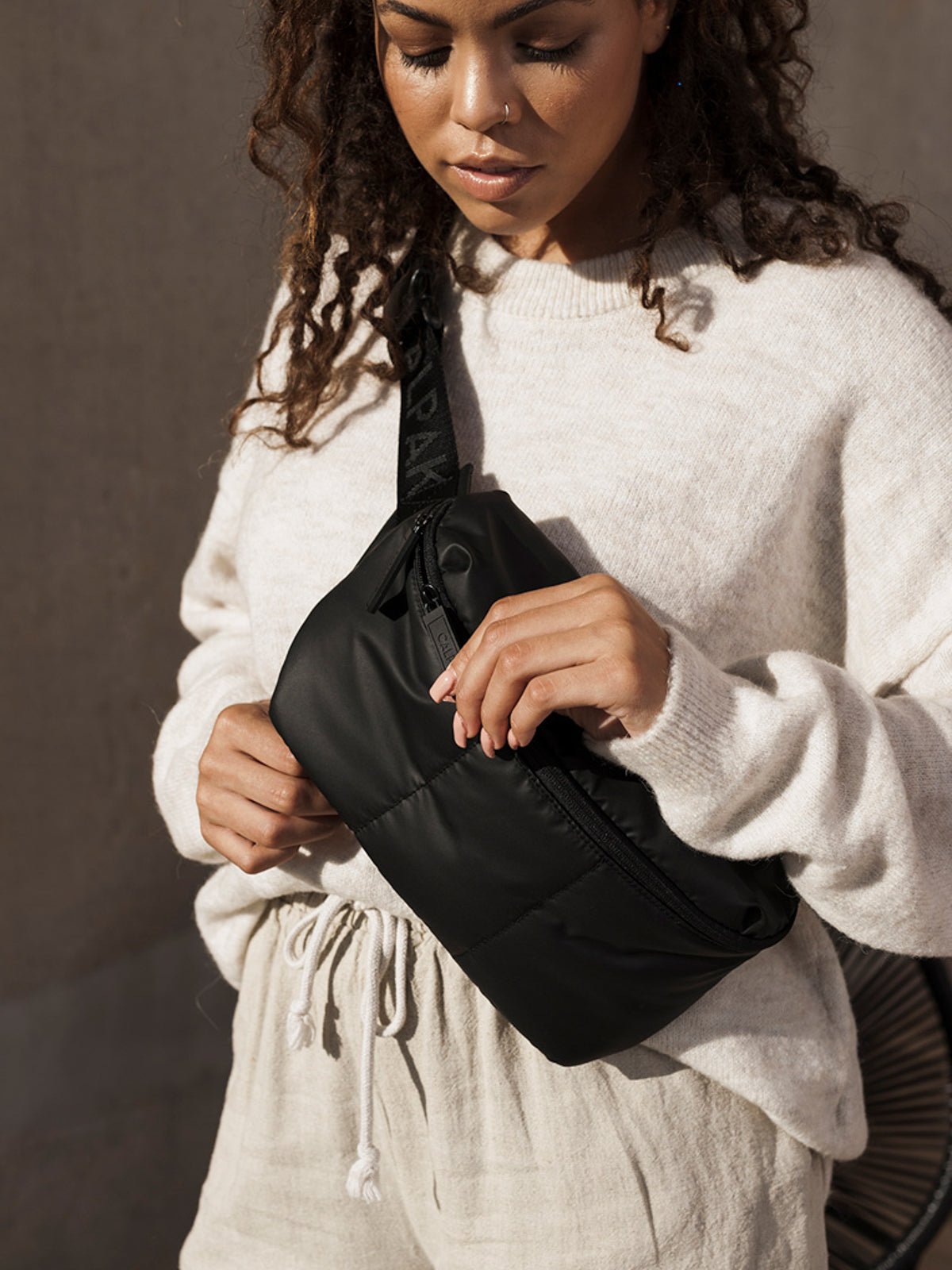Model carrying Luka belt bag with adjustable crossbody strap in matte black