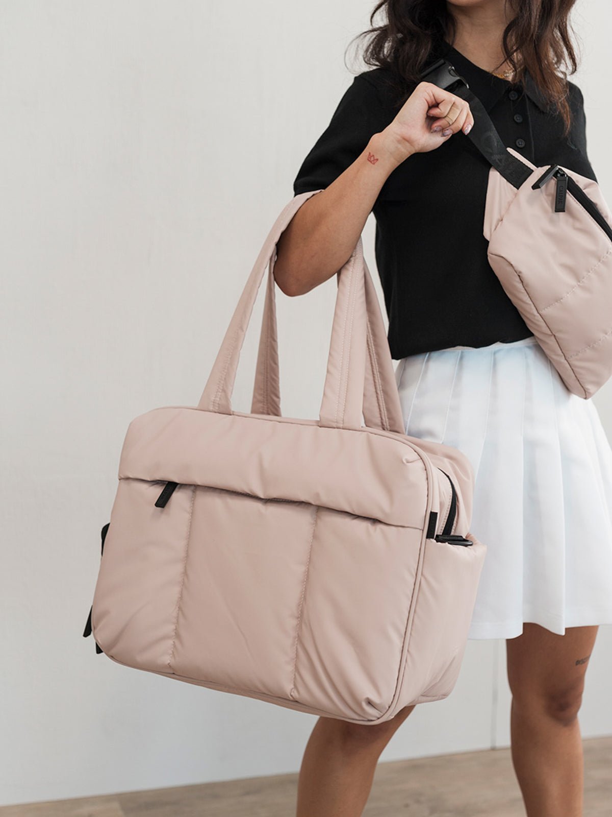 Model carrying Luka crossbody bag and Luka Duffel in rose quartz