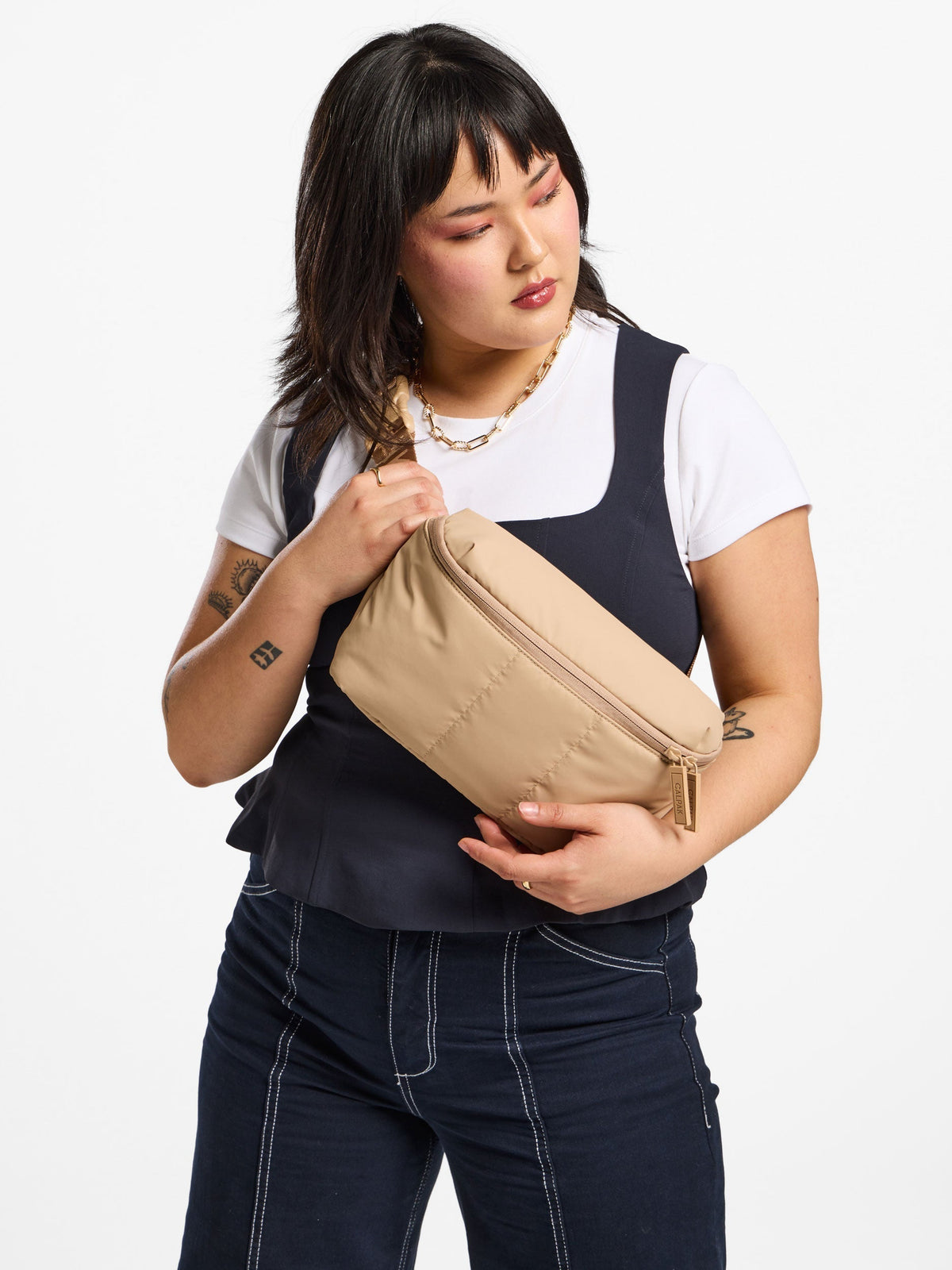 Model wearing CALPAK Luka Belt Bag as crossbody bag in latte; BB1901-LATTE