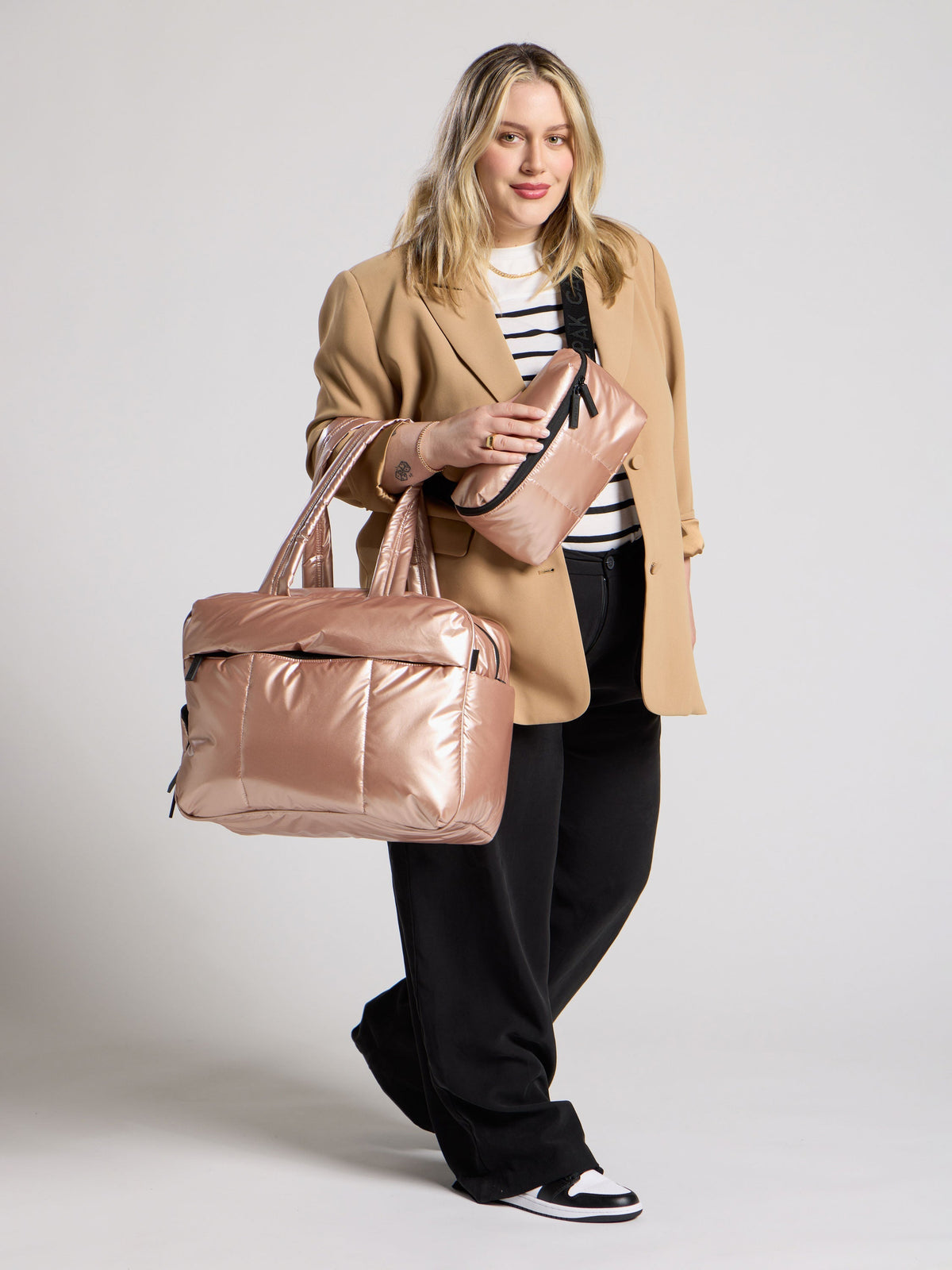 CALPAK Model wearings metallic rose gold belt bag as crossbody bag and luka duffel bag over shoulder; BB1901-ROSE-GOLD