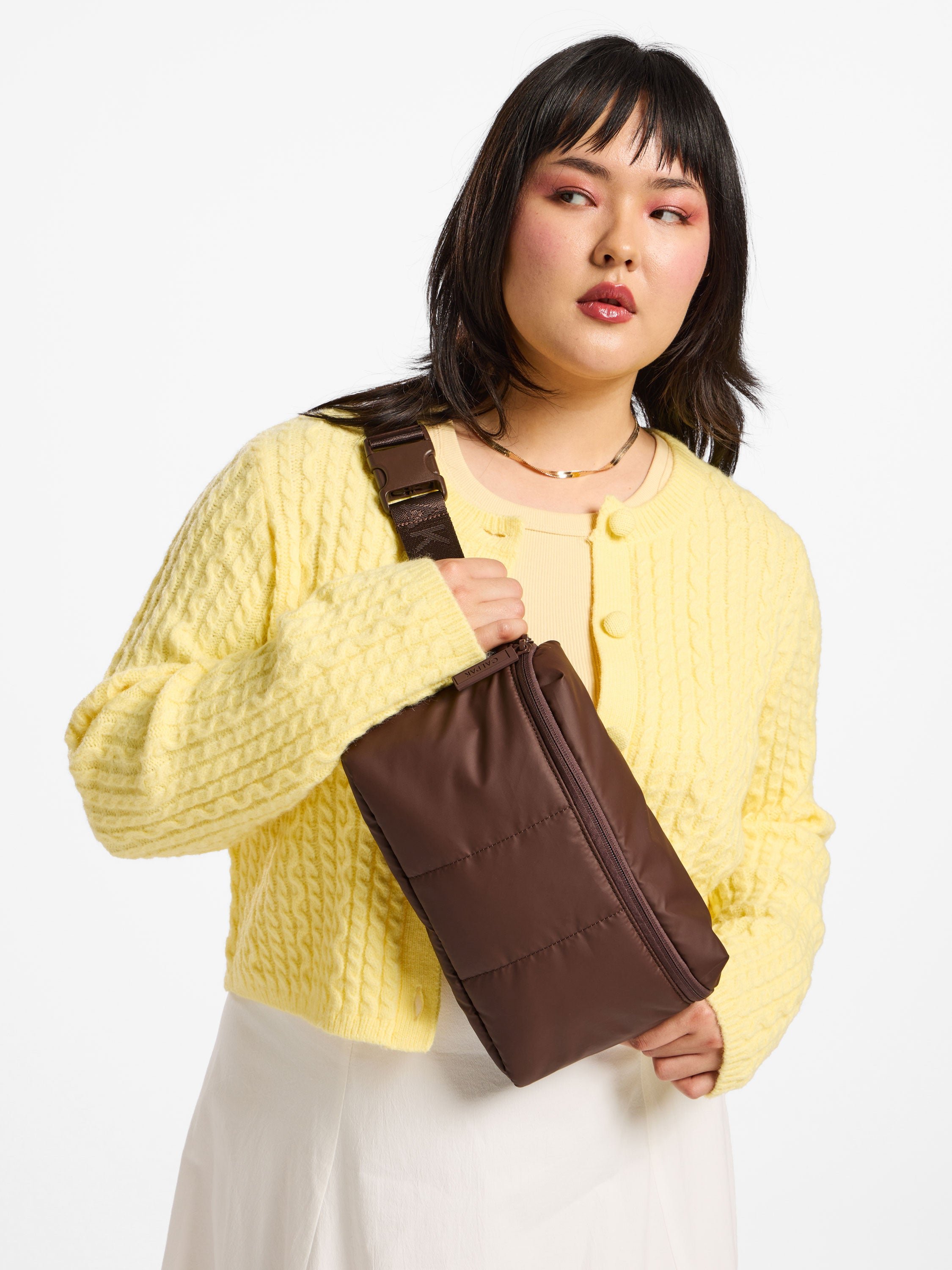 Model wearing CALPAK Luka Belt Bag in walnut as crossbody bag