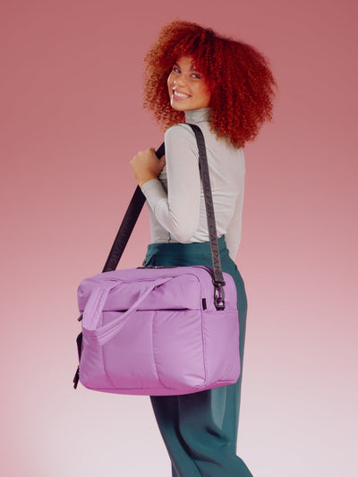 Model wearing CALPAK Luka Duffel in lavender over shoulder with detachable shoulder strap