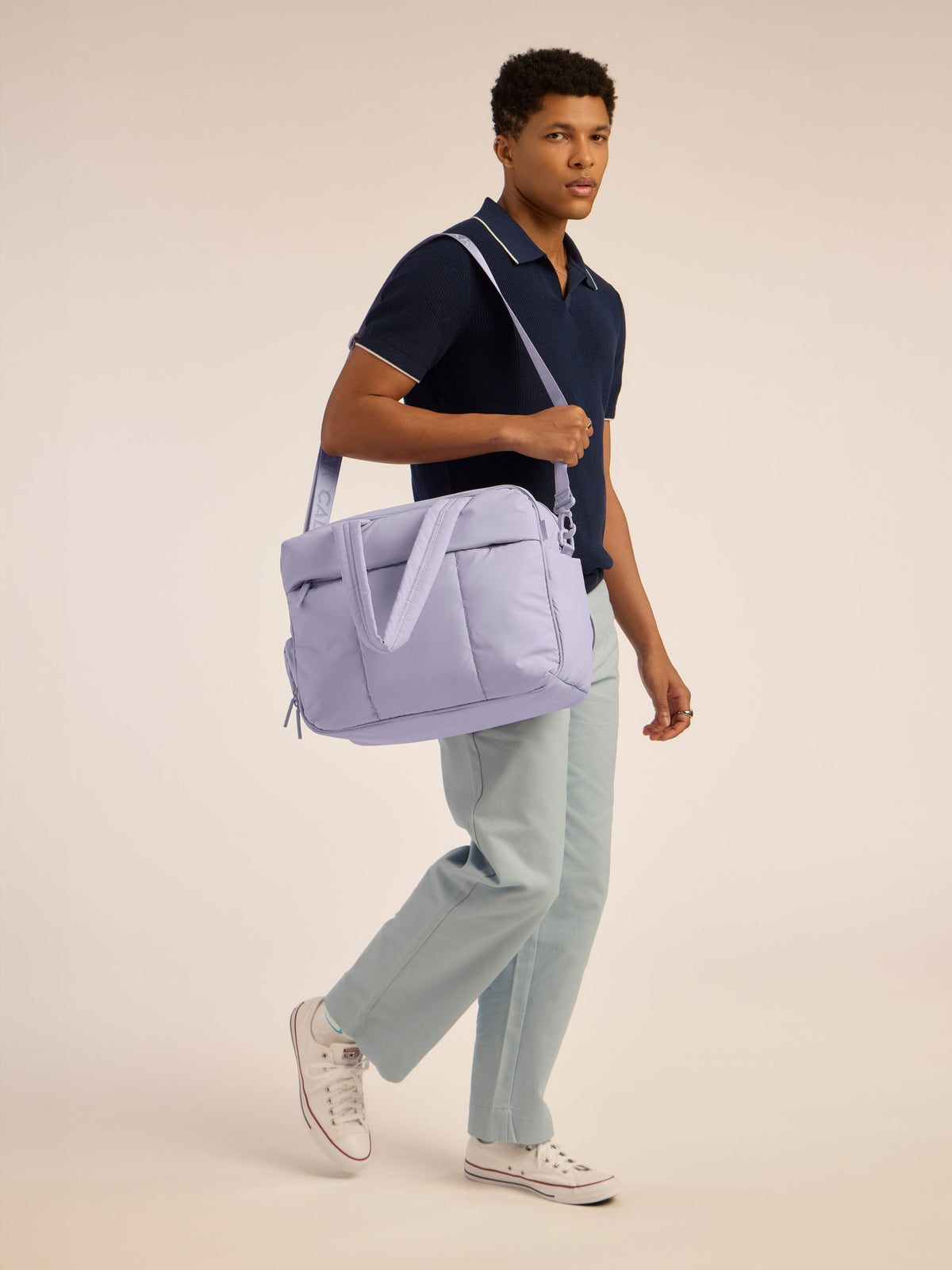 Male model holding CALPAK Luka Duffel monochrome in purple lavender Orchid by shoulder strap; DSM1901-ORCHID
