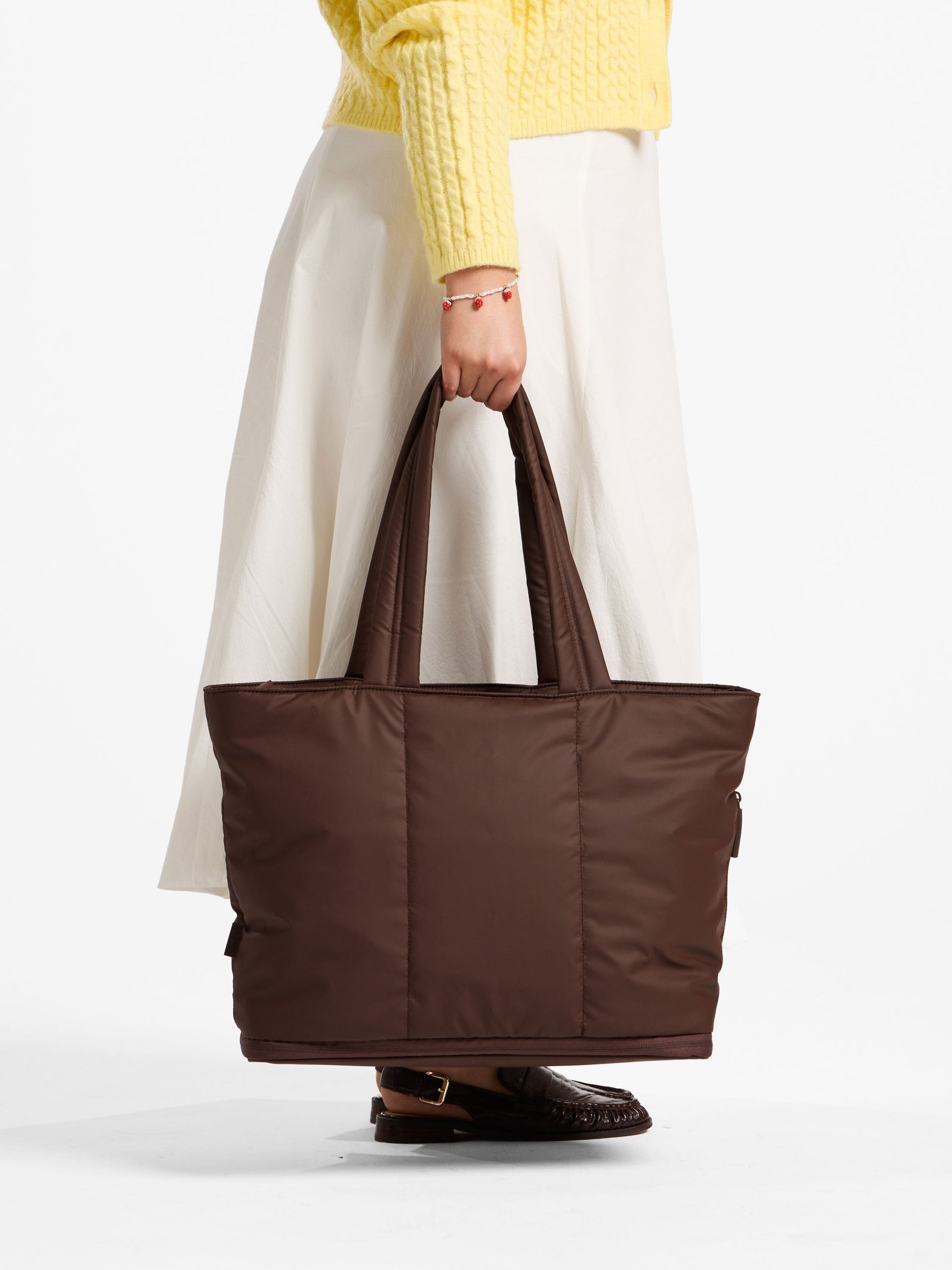 Model holds CALPAK Luka Expandable Laptop Tote Bag by handle in walnut; ALT2201-WALNUT