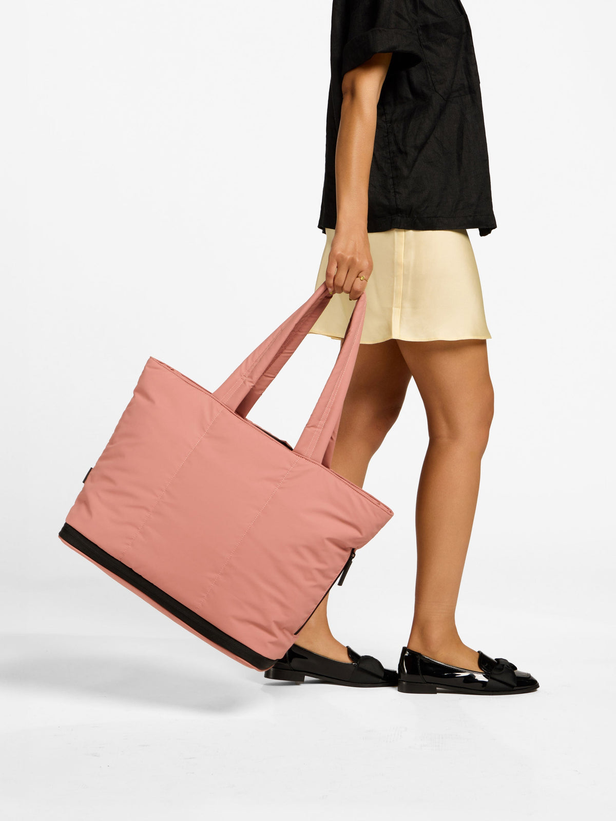 Model holding CALPAK Luka Expandable Laptop Tote in peony; ALT2201-PEONY