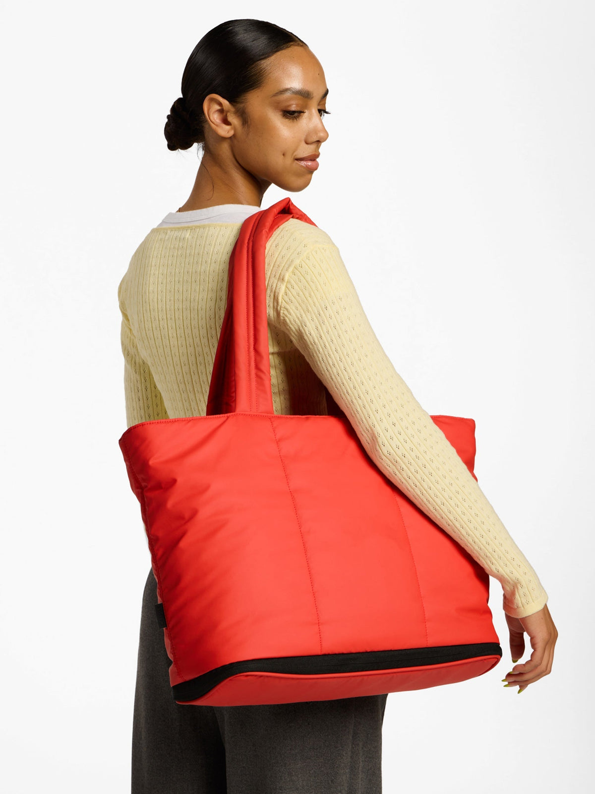 Model wearing CALPAK Luka Expandable Laptop Tote Bag over shoulder in rouge red; ALT2201-ROUGE