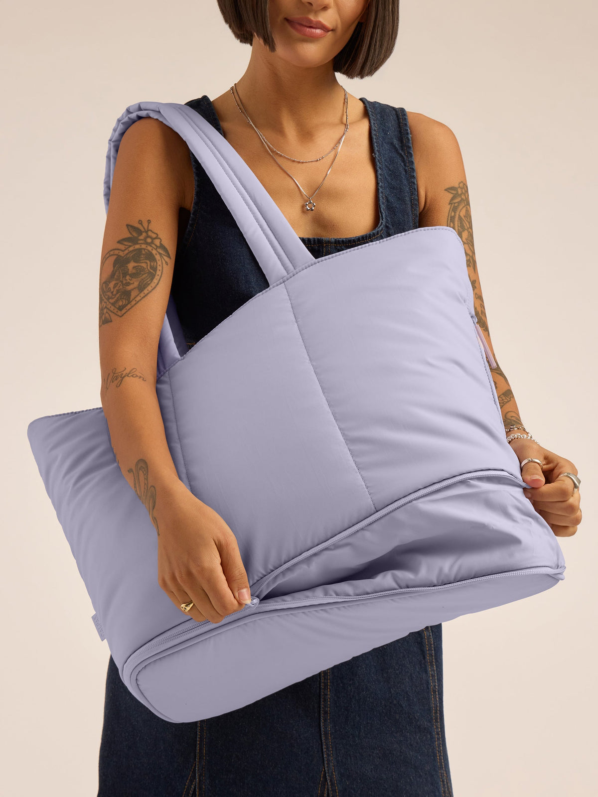 Model unzipping expandable portion of CALPAK Luka Expandable Tote in lavender purple Orchid; ALT2201-ORCHID