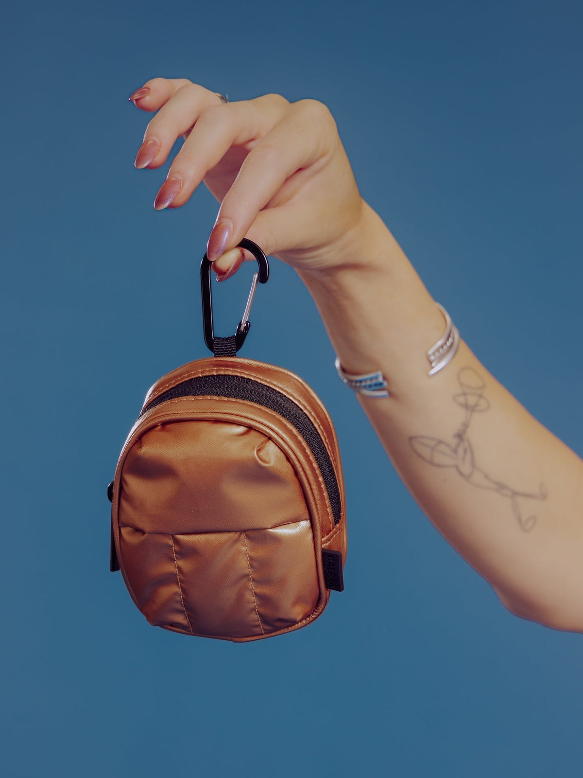 Model holding up CALPAK Luka Key Pouch in copper by the carabiner clip; AMB2201-COPPER