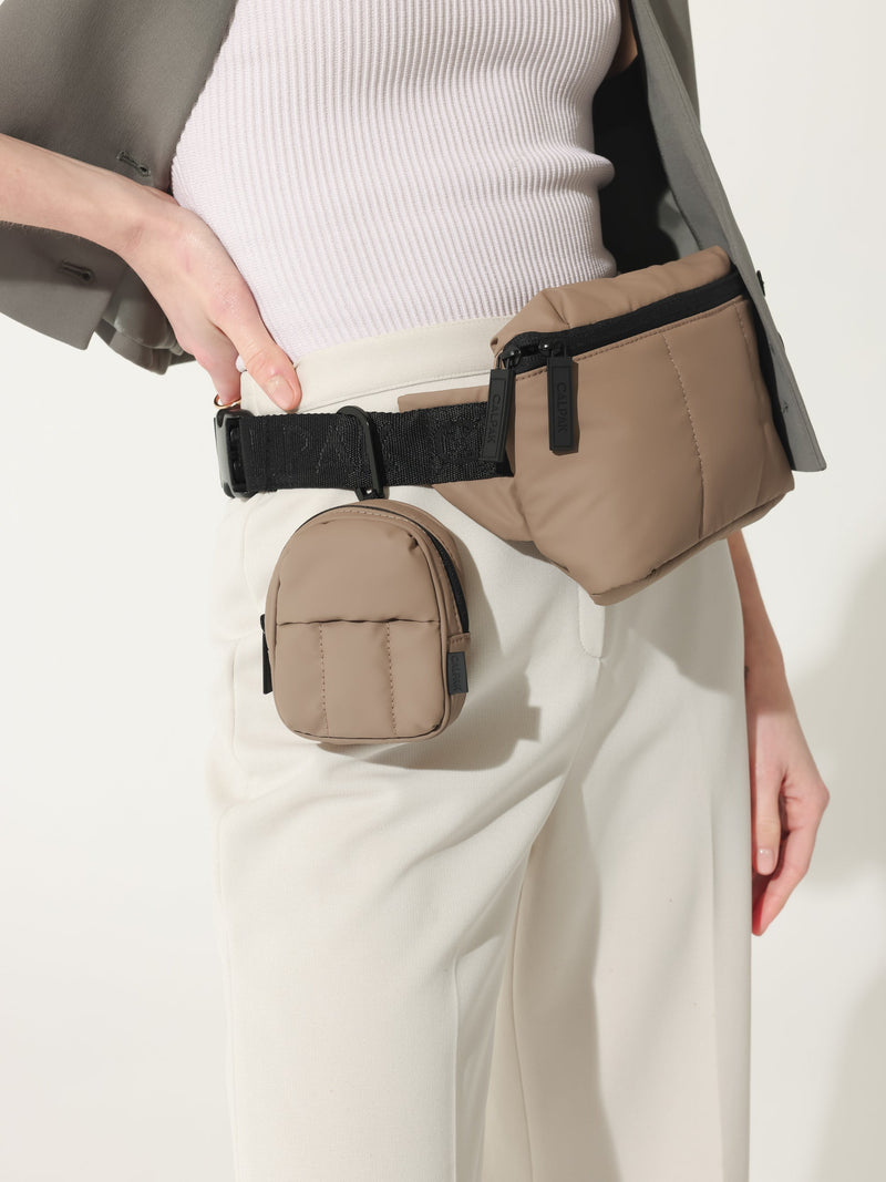 The Luka Key Pouch in light brown chocolate, shown in a lifestyle setting attached to a model’s belt bag