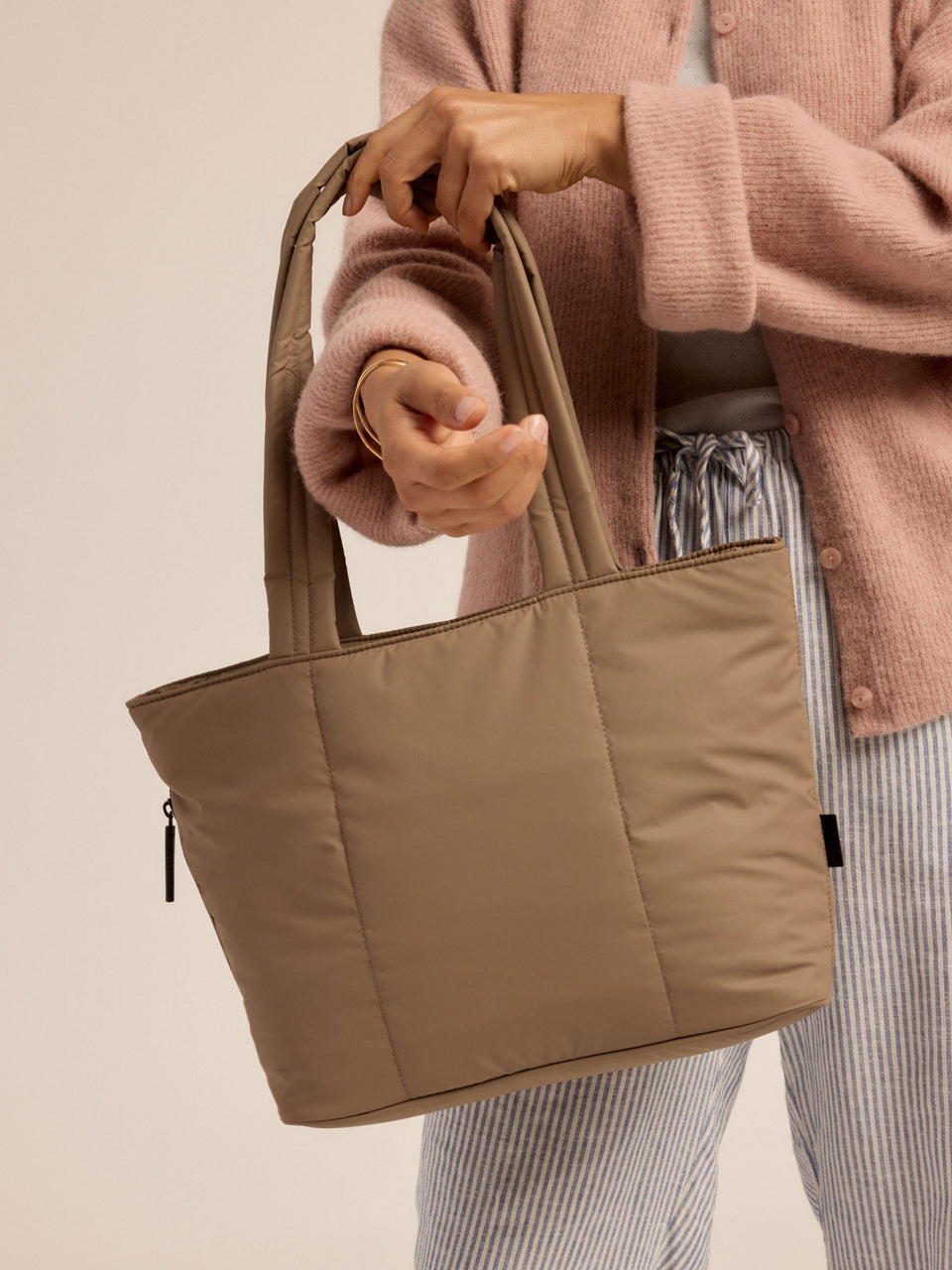 Model placing chocolate CALPAK Luka Mini Tote over forearm; ALM2401-CHOCOLATE