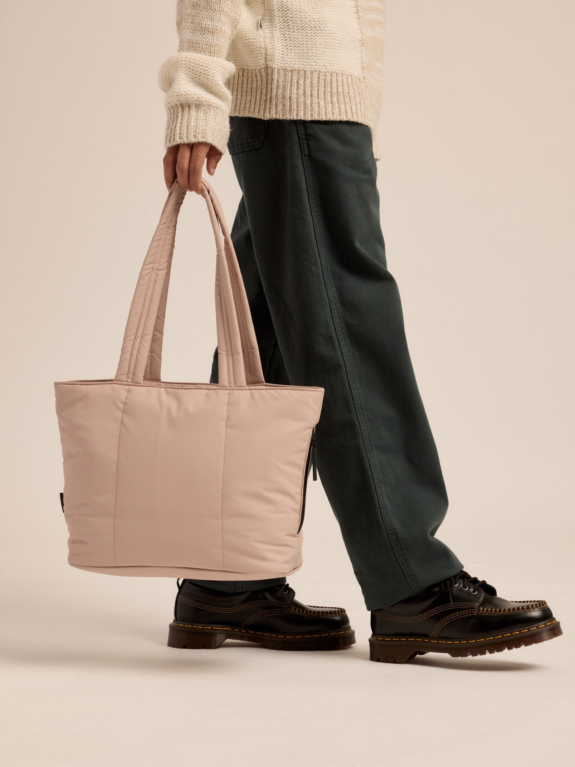 Model walking and holding CALPAK Luka Mini Tote by durable, padded shoulder strap in rose quartz pink; ALM2401-ROSE-QUARTZ