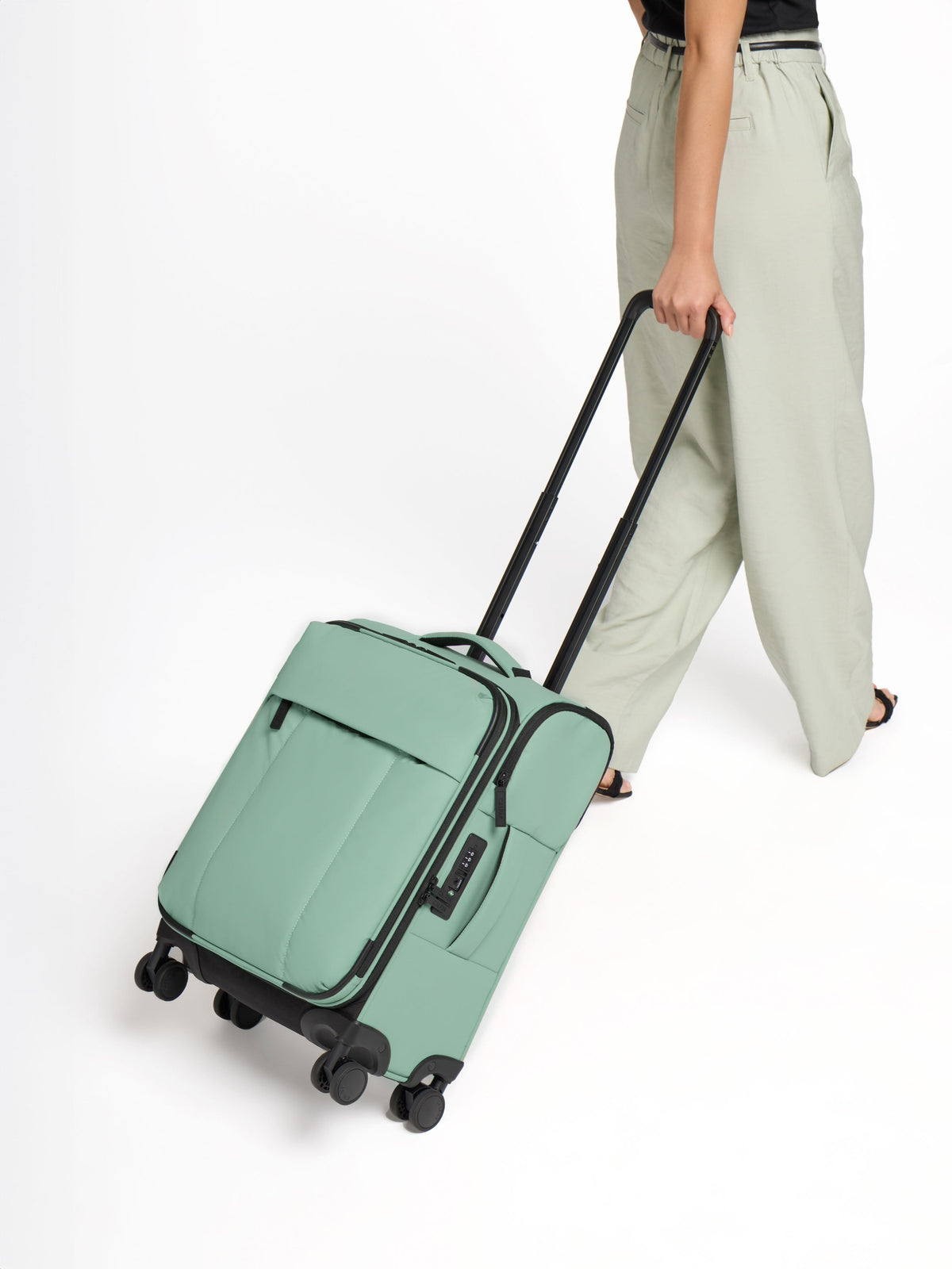 Model rolling CALPAK Luka Soft-Sided Carry-On Luggage in sage green; LSM1020-SAGE