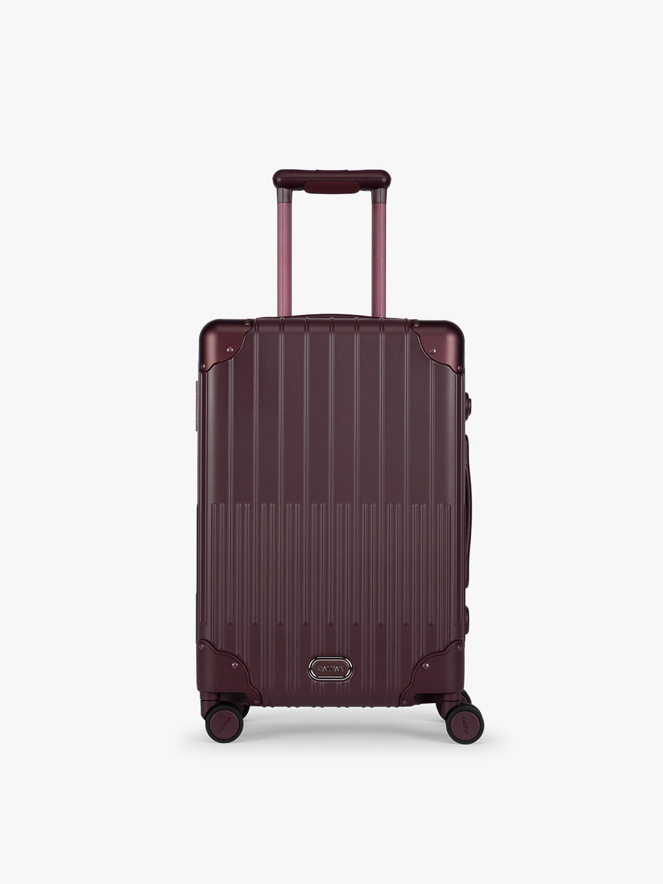CALPAK Vault deep red Dark Cherry hard-shell spinner Carry On Luggage with a telescoping handle extended, featuring a deep red leatherette side handle and trim, set against a plain light gray background; LVT1020-DARK-CHERRY