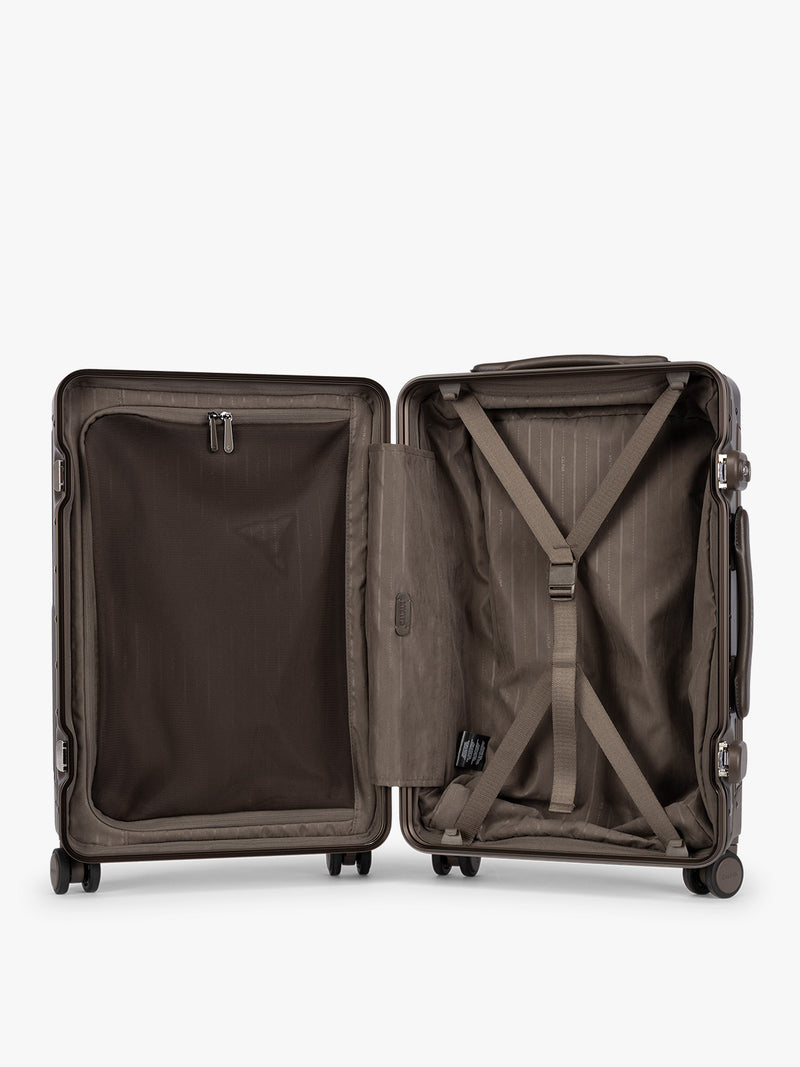 Opened CALPAK Vault brown Mushroom hard-shell spinner Carry On Luggage with a telescoping handle extended, featuring a black leatherette side handle and trim, set against a plain light gray background