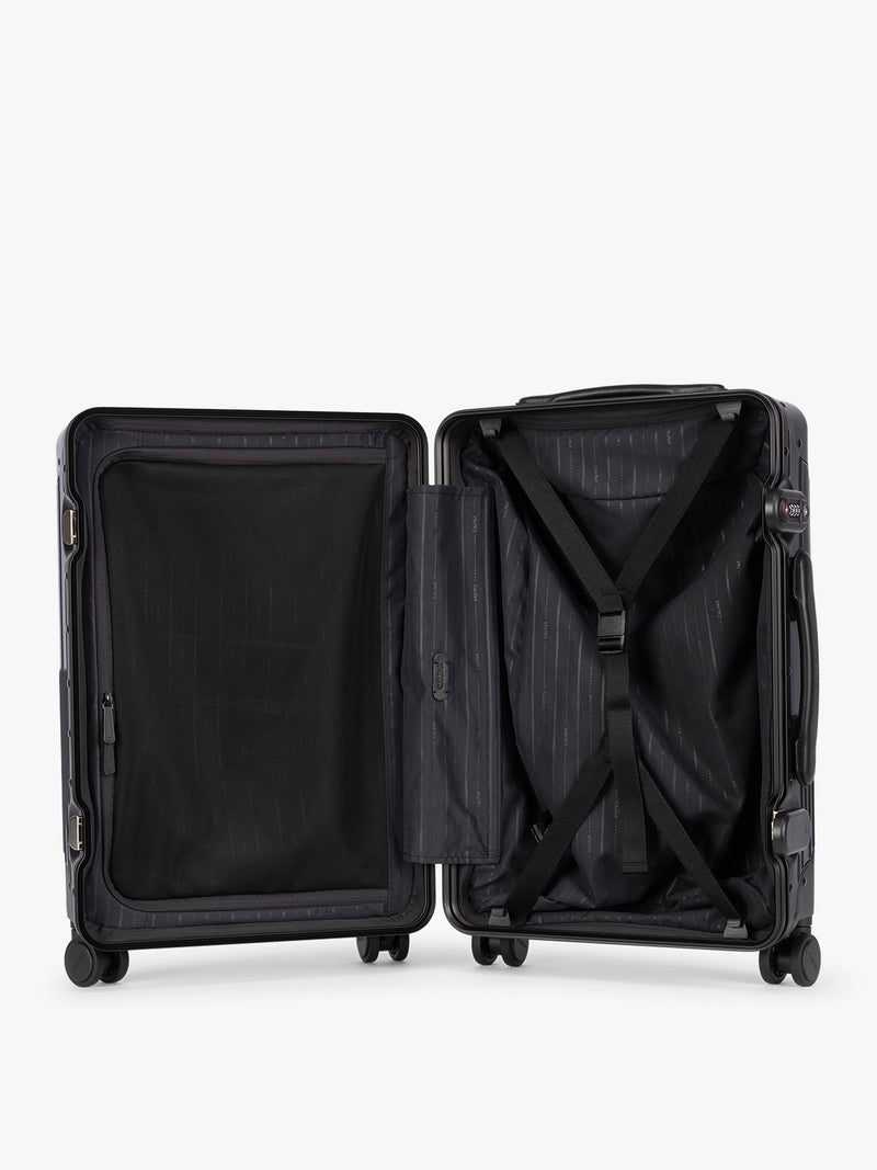Opened CALPAK Vault black Onyx hard-shell spinner Carry On Luggage with a telescoping handle extended, featuring a Black leatherette side handle and trim, set against a plain light gray background