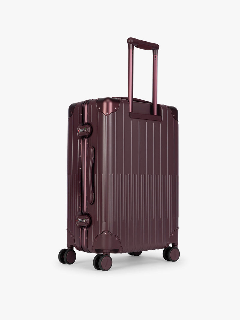 Backside of CALPAK Vault Luggage Dark Cherry deep red hard-shell spinner suitcase with a ribbed vertical design, shown from the front against a clean white background