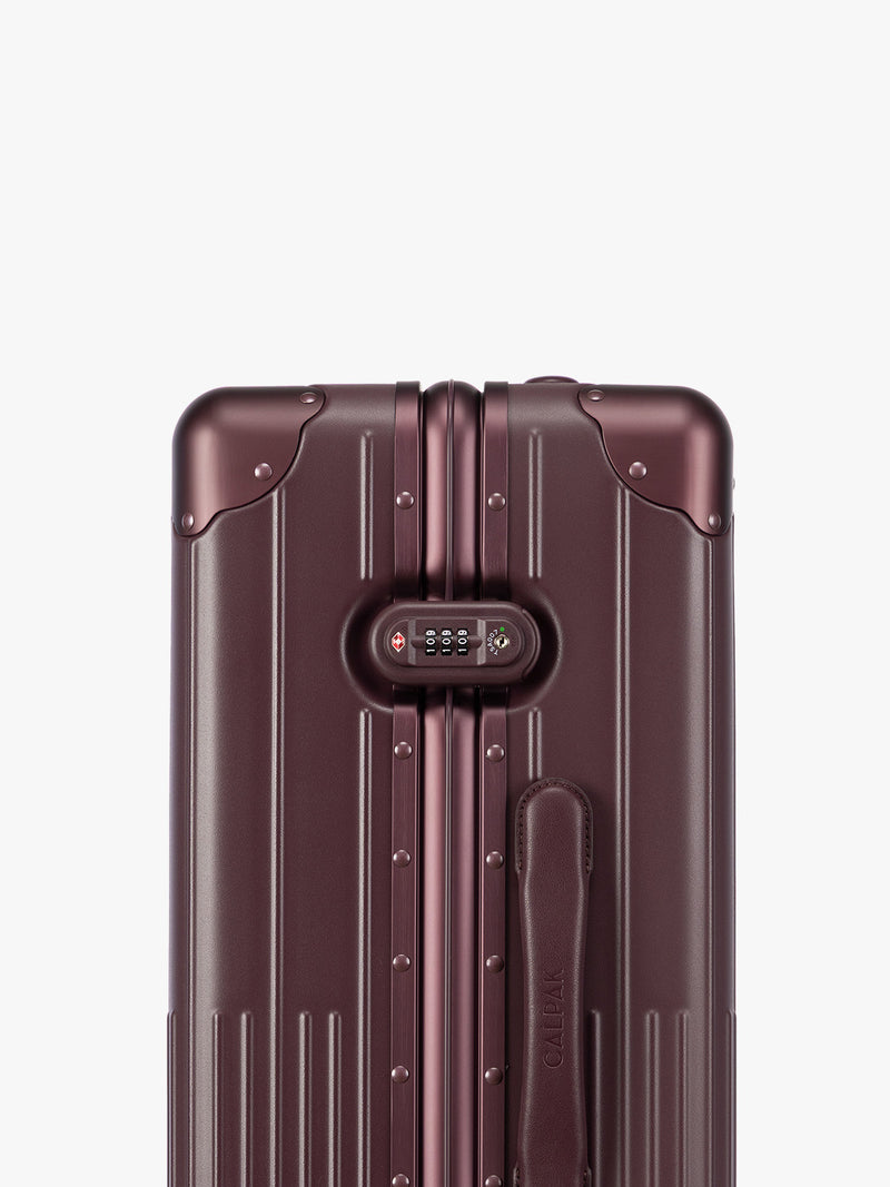 Closeup of TSA Lock of CALPAK Vault Luggage Dark Cherry deep red hard-shell spinner suitcase with a ribbed vertical design, shown from the front against a clean white background