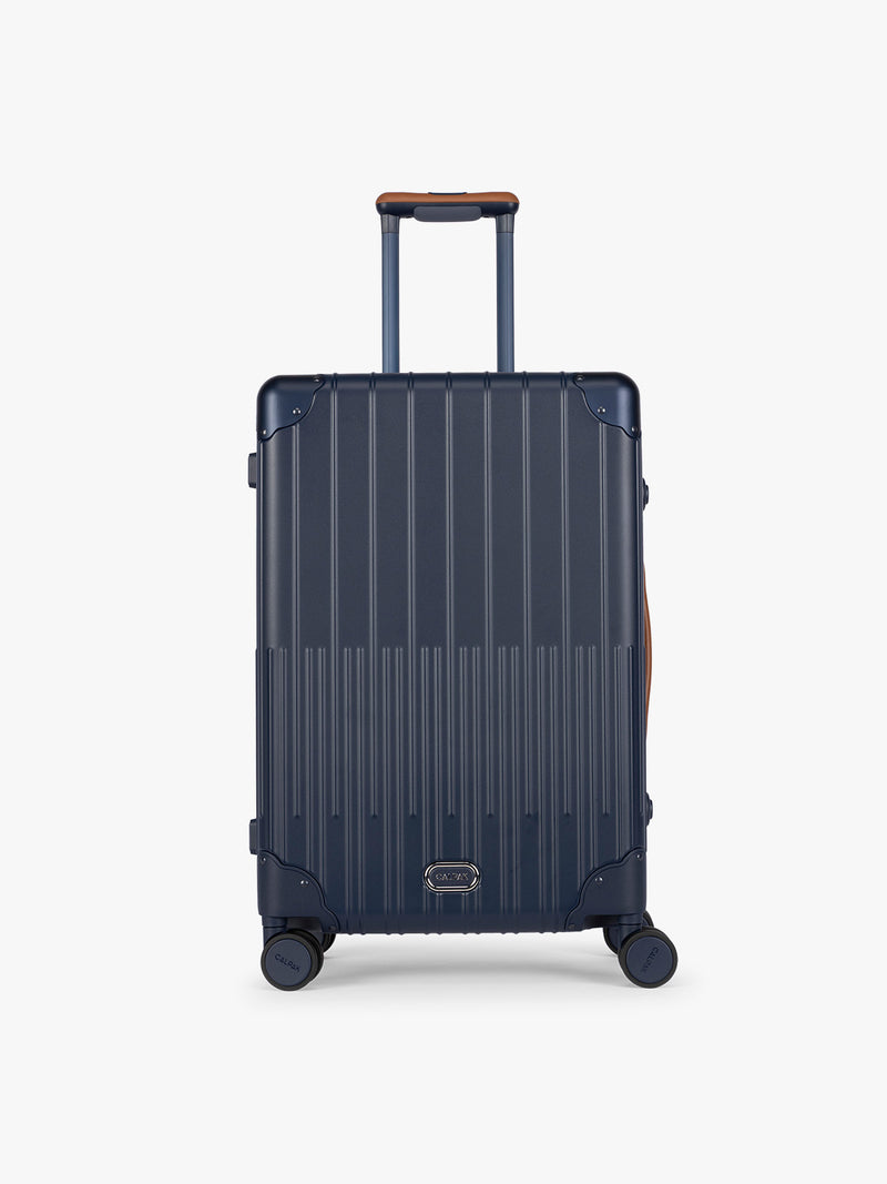 CALPAK Vault Luggage blue Navy hard-shell spinner suitcase with a ribbed vertical design, shown from the front against a clean white background