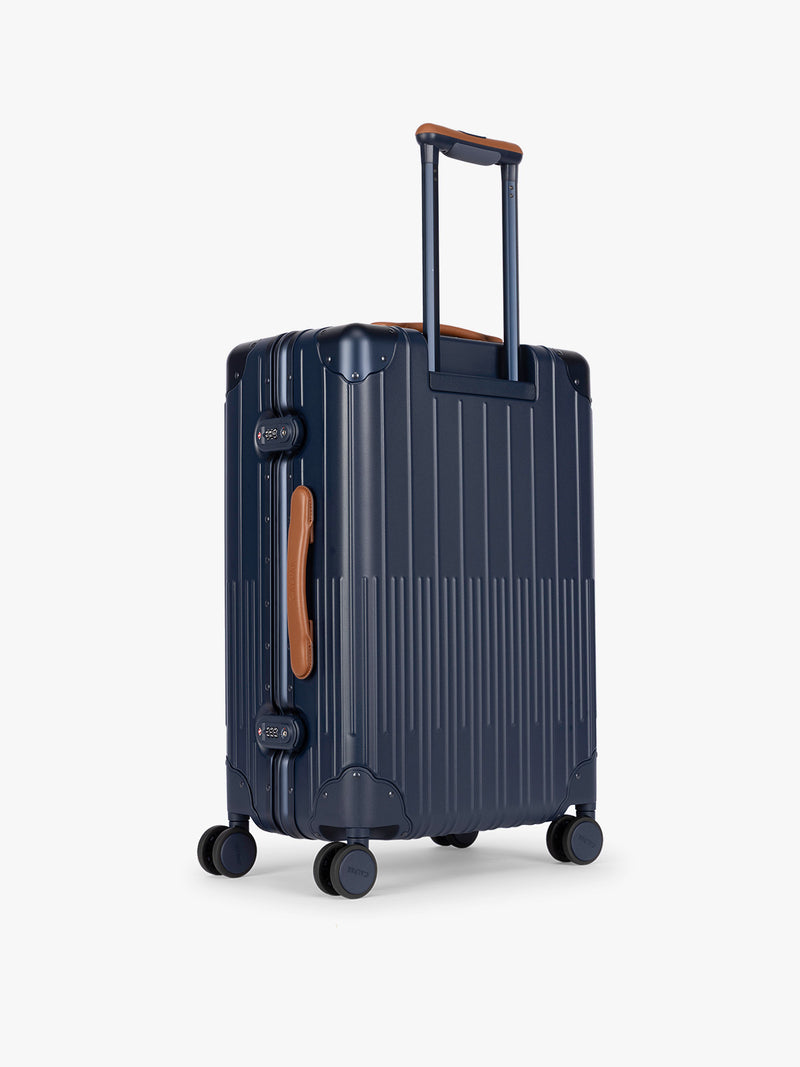 Backside of CALPAK Vault Luggage blue Navy hard-shell spinner suitcase with a ribbed vertical design, shown from the front against a clean white background
