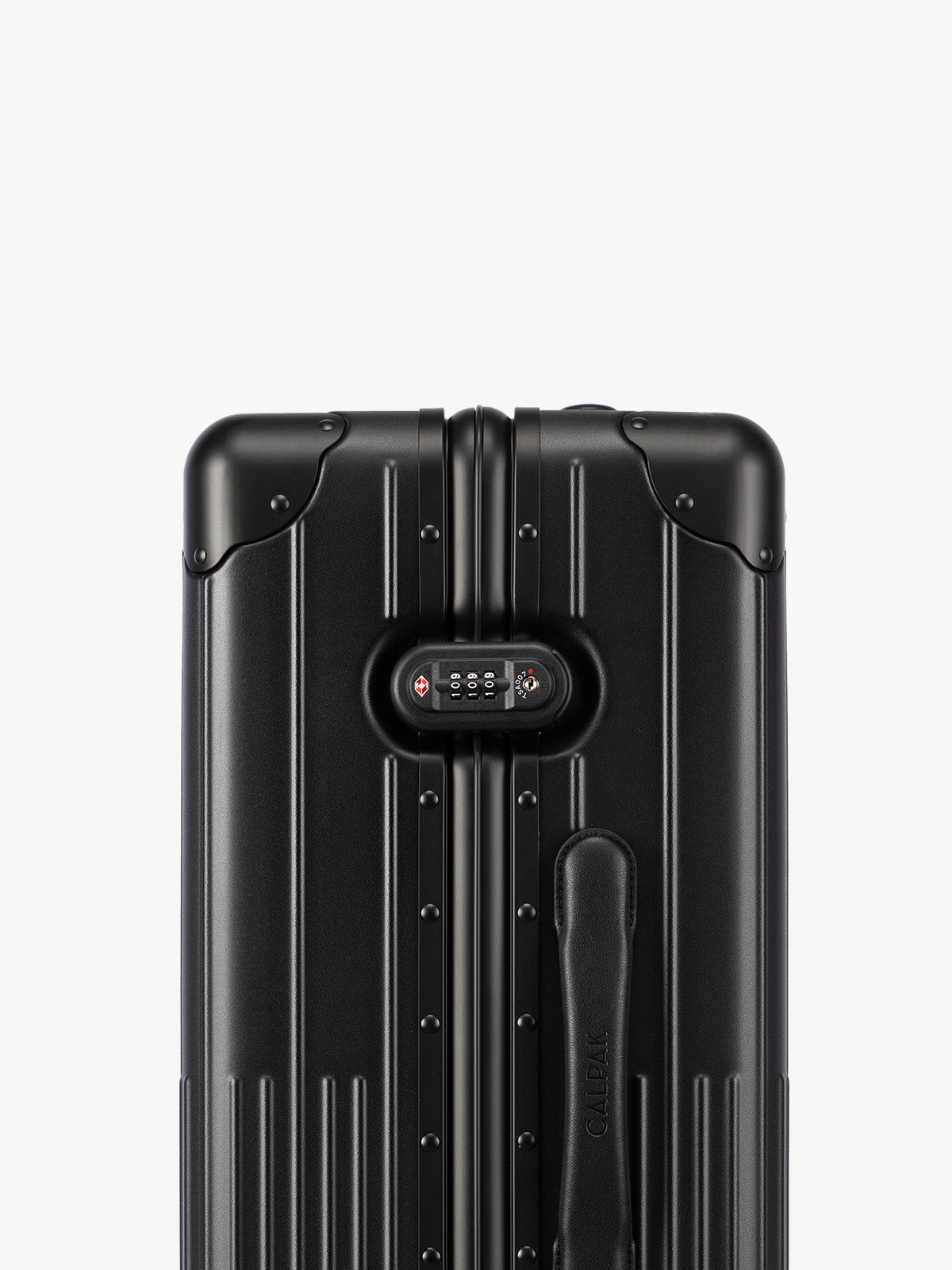 Closeup of TSA-approved lock of CALPAK Vault Luggage Onyx black hard-shell spinner suitcase with a ribbed vertical design, shown from the front against a clean white background; LVT1024-ONYX