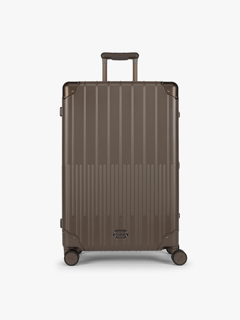 CALPAK Large Vault Luggage in brown Mushroom with hard-shell spinner suitcase with a ribbed vertical design, shown from the front on a light gray background