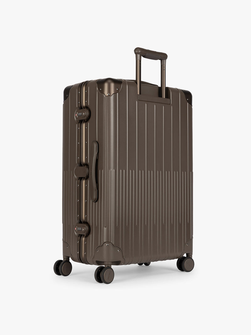 Backside of CALPAK Large Vault Luggage in brown Mushroom with hard-shell spinner suitcase with a ribbed vertical design, shown from the front on a light gray background