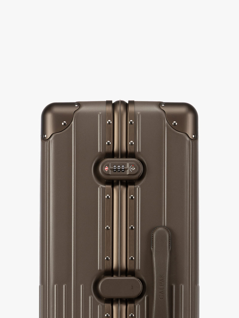 Closeup of TSA-approved lock of CALPAK Large Vault Luggage in brown Mushroom with hard-shell spinner suitcase with a ribbed vertical design, shown from the front on a light gray background