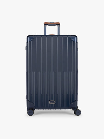 CALPAK Large Vault Luggage in blue Navy with hard-shell spinner suitcase with a ribbed vertical design, shown from the front on a light gray background; LVT1028-NAVY view 1