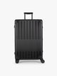 CALPAK Large Vault Luggage in black Onyx with hard-shell spinner suitcase with a ribbed vertical design, shown from the front on a light gray background; LVT1028-ONYX
