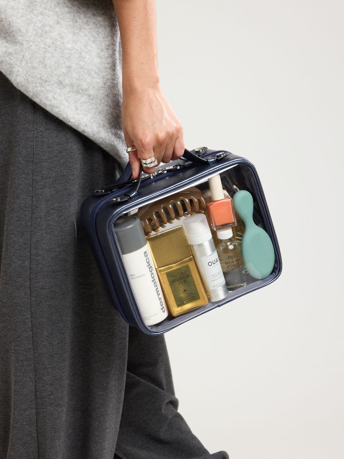 Person holding the CALPAK Clear Cosmetic Case in dark blue French Blue; CMM2201-METALLIC-INDIGO