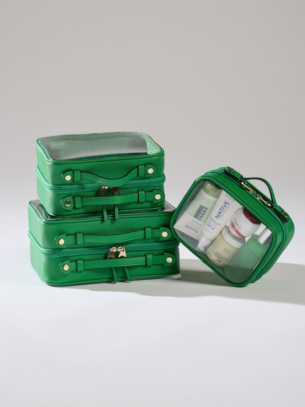 CALPAK Small Clear Cosmetic Case leaning besides Medium Clear Cosmetic Case and Large Clear Cosmetic Case in green apple; CMM2201-GREEN-APPLE
