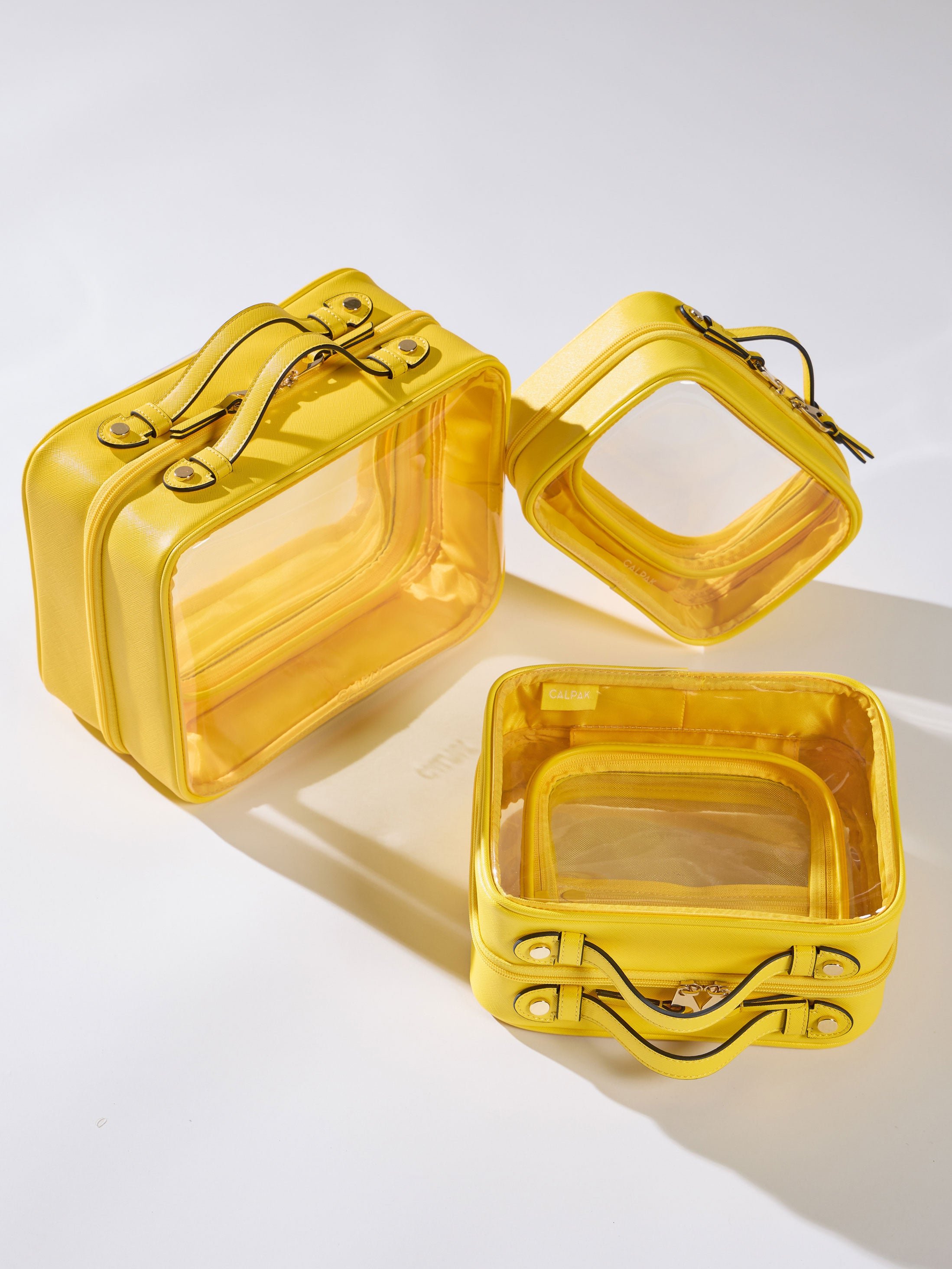 Yellow CALPAK Clear Cosmetic Cases in Medium, Large, and Small for organizing skin care items