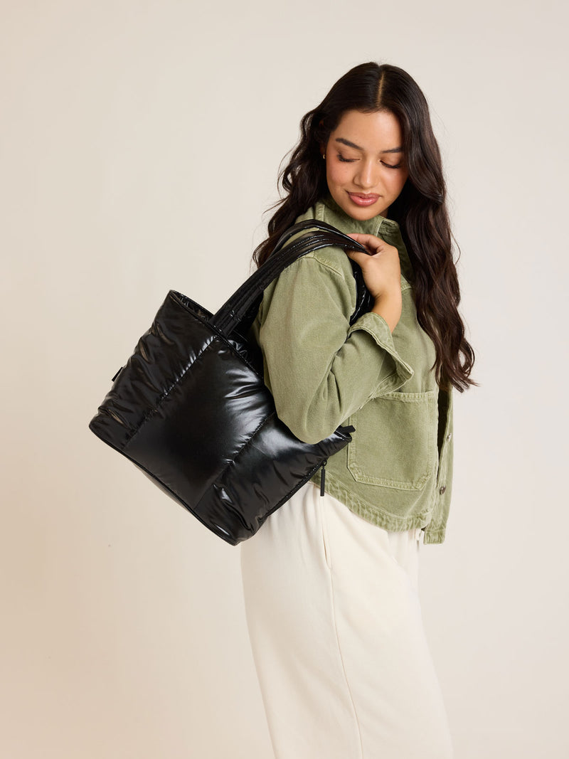 Model wearing CALPAK Luka Mini Tote in shiny Glazed Black on a white background