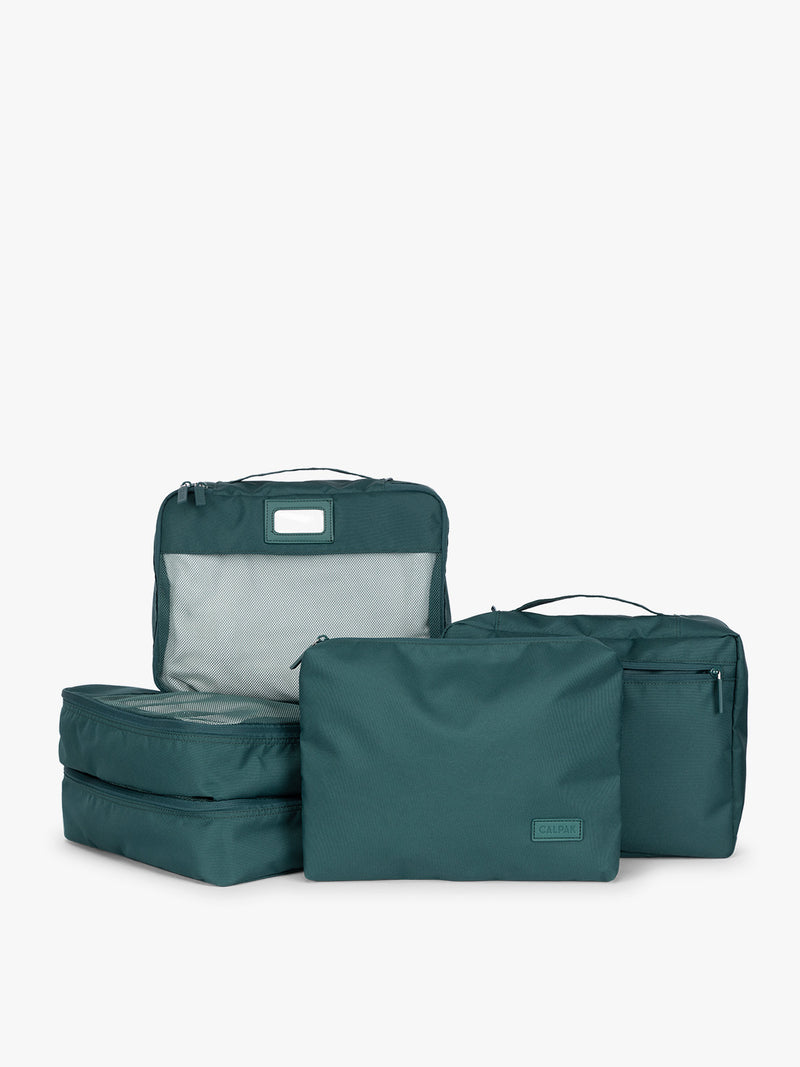 Deep green teal Kale CALPAK 5-piece travel packing cubes set which includes three mesh cubes, a flat cube, and a zippered organizer, displayed on a clean white background