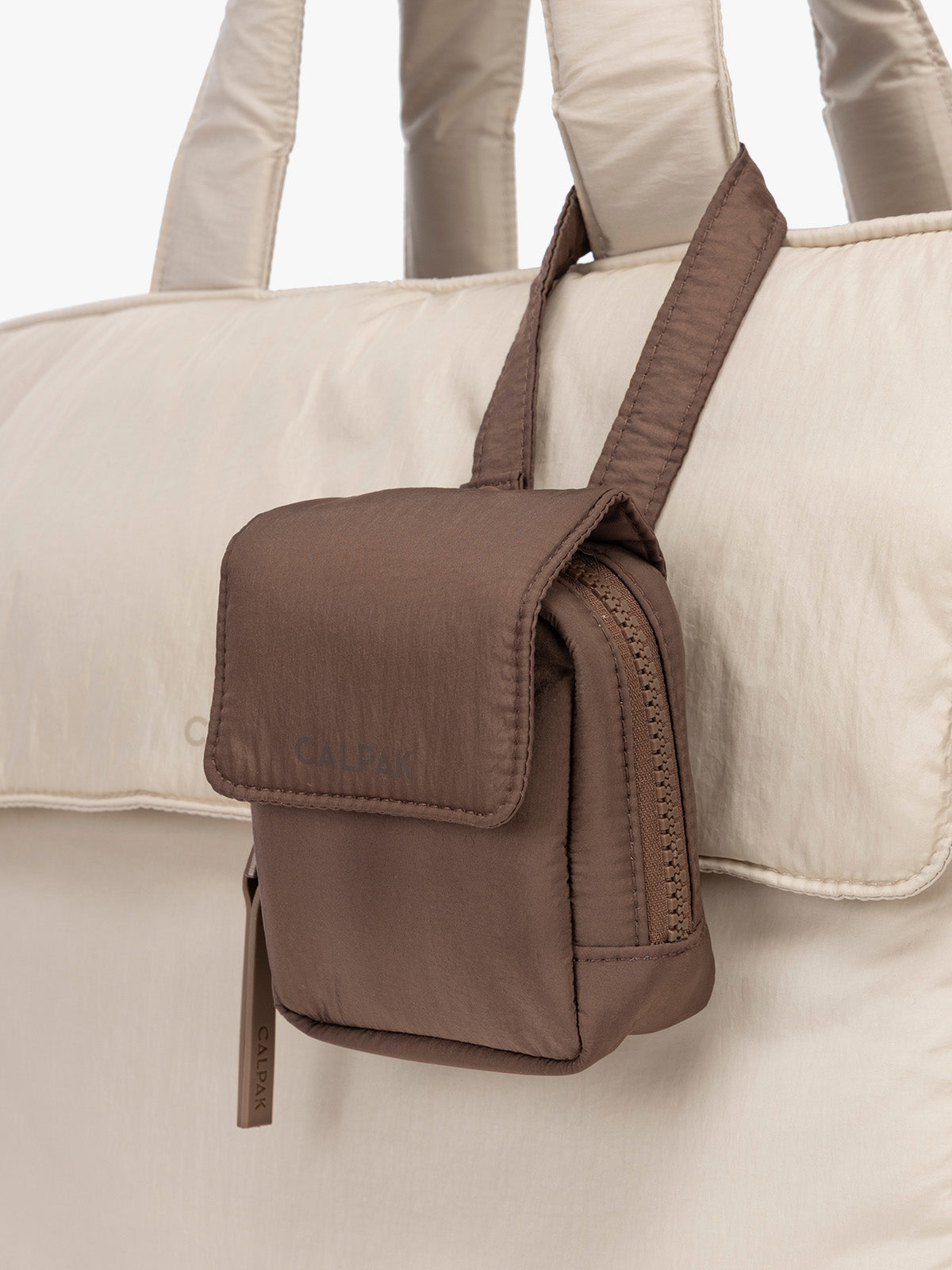 CALPAK Baby Collection Pacifier Pouch in brown Hazelnut clipped onto white bag; PCB2501-HAZELNUT