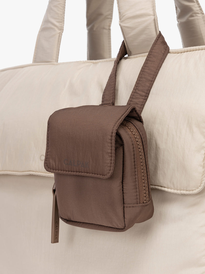 CALPAK Baby Collection Pacifier Pouch in brown Hazelnut clipped onto white bag