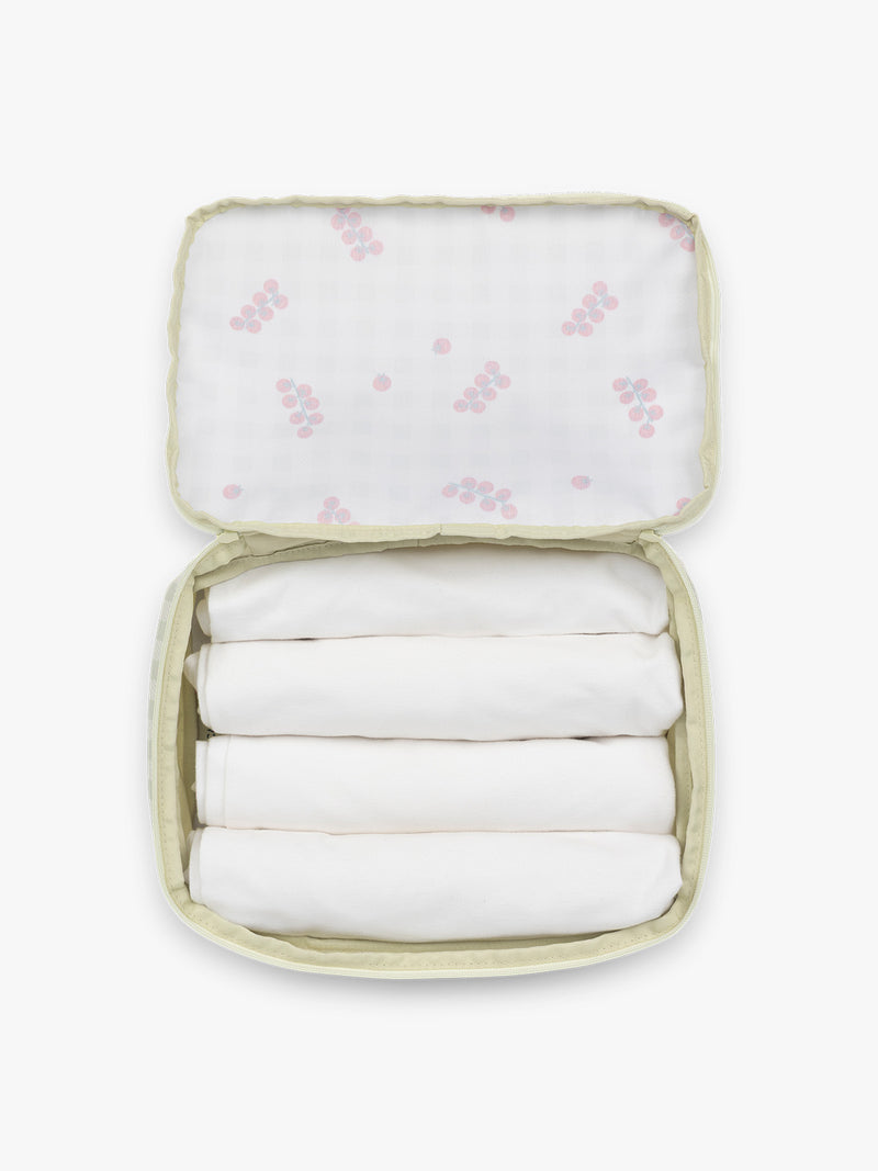 Opened CALPAK Medium Compression Packing Cubes in white and green gingham pattern with tomato print