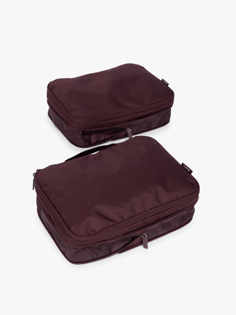 Two burgundy Dark Cherry CALPAK Medium Compression Packing Cubes with zippers shown on a clean white background shown uncompressed