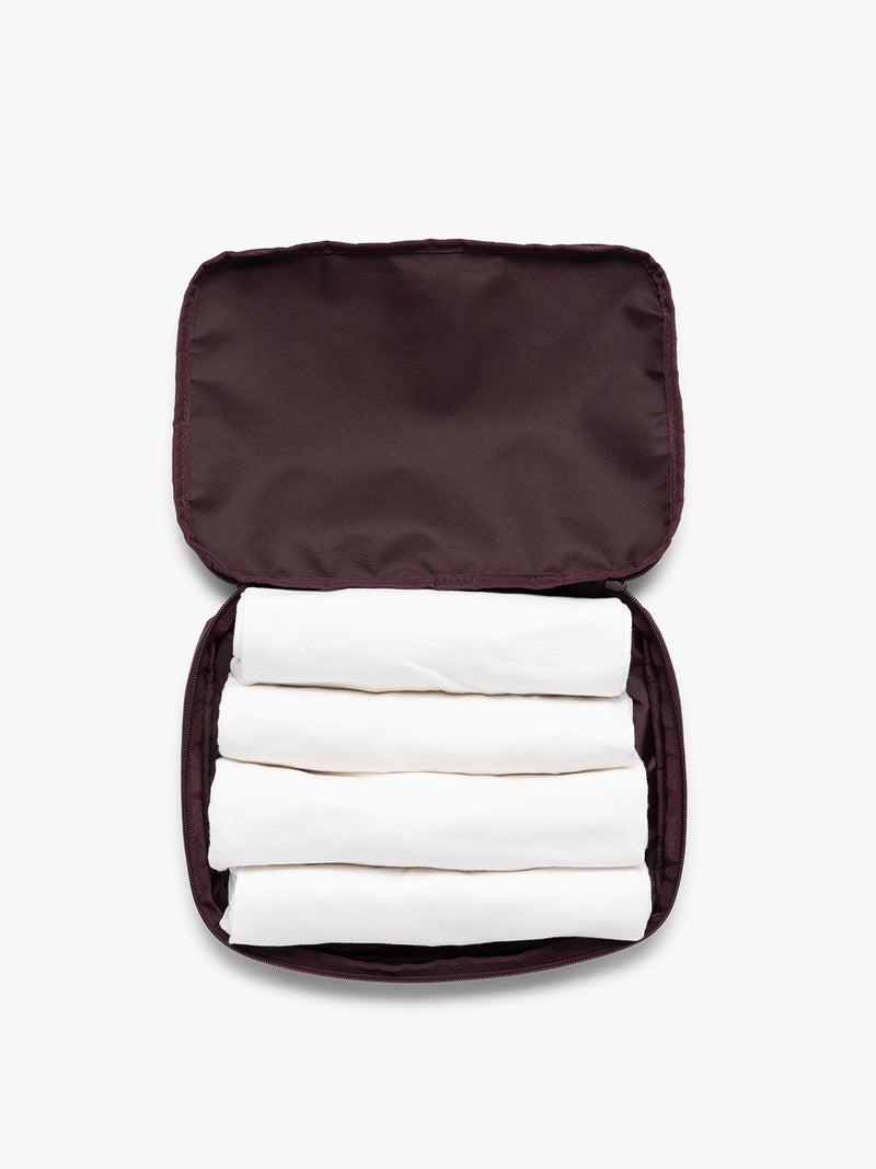 Opened view with clothing in the burgundy Dark Cherry CALPAK Medium Compression Packing Cubes with zippers shown on a clean white background