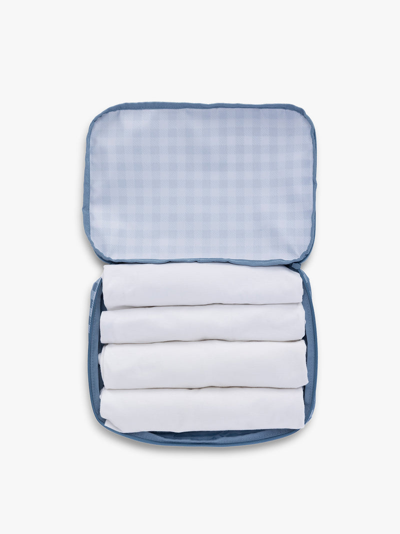 Towels rolled up in CALPAK Medium Compression Packing Cubes (Set of 2) in white and blue gingham print in French Blue Gingham