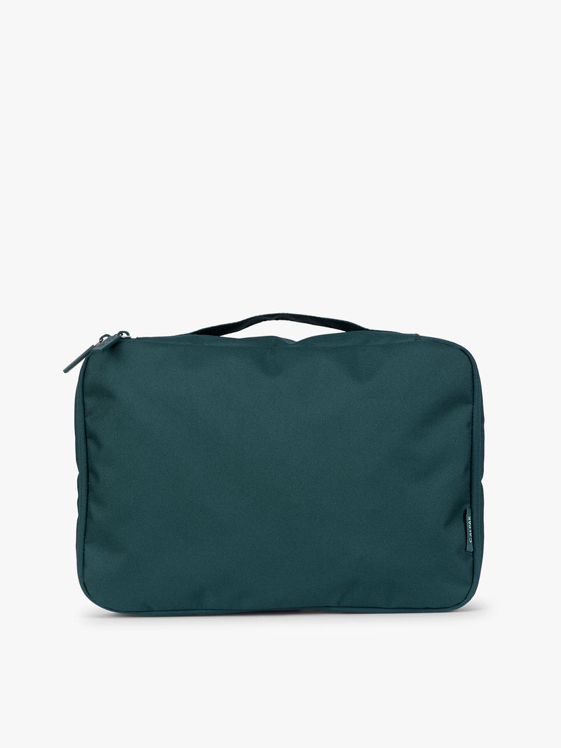 Closeup of a dark green teal Kale CALPAK Medium Compression Packing Cubes with zippers shown on a clean white background