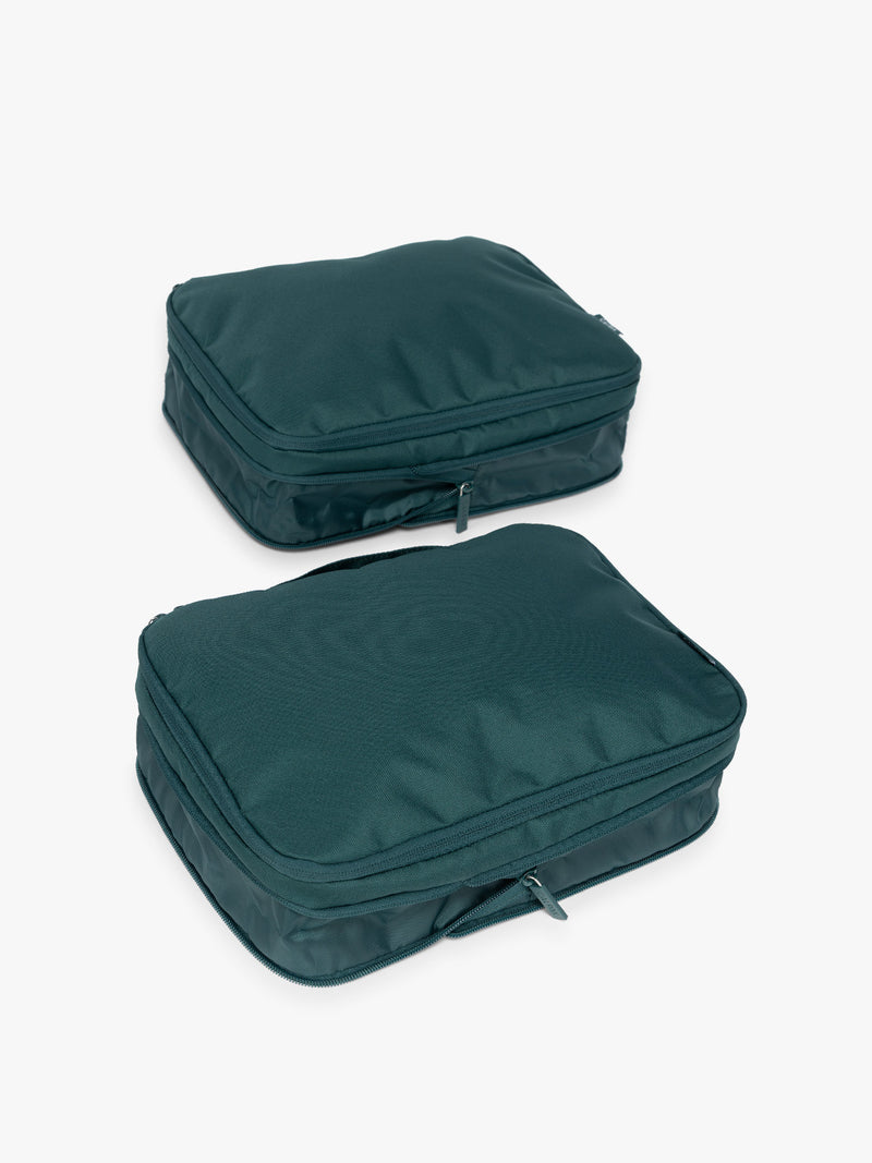Two dark green teal Kale CALPAK Medium Compression Packing Cubes with zippers shown on a clean white background in an uncompressed view