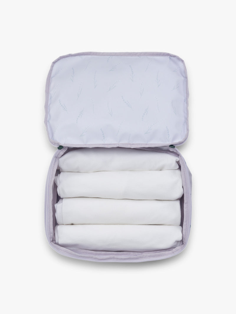 Towels rolled up in the CALPAK Medium Compression Packing Cubes (Set of 2) in light purple with lavender print in Lavender Bloom