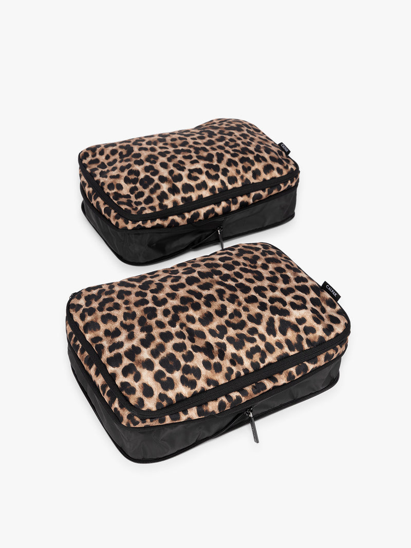 Two tan and black animal print Leopard CALPAK Medium Compression Packing Cubes with zippers shown on a clean white background uncompressed view