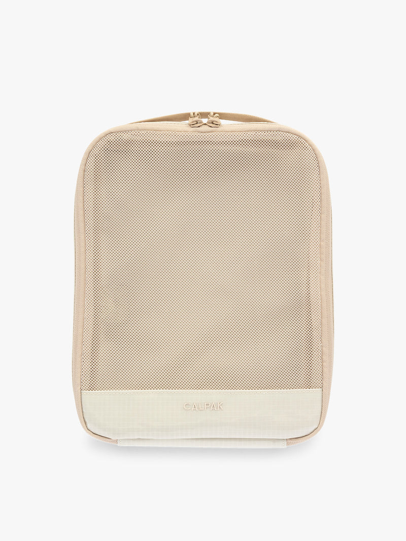 Medium size packing cube of the CALPAK Terra 5-Piece Packing Cube Set in off-white beige White Sands with two small cubes, two medium cubes, and one large mesh cube with zippers and mesh