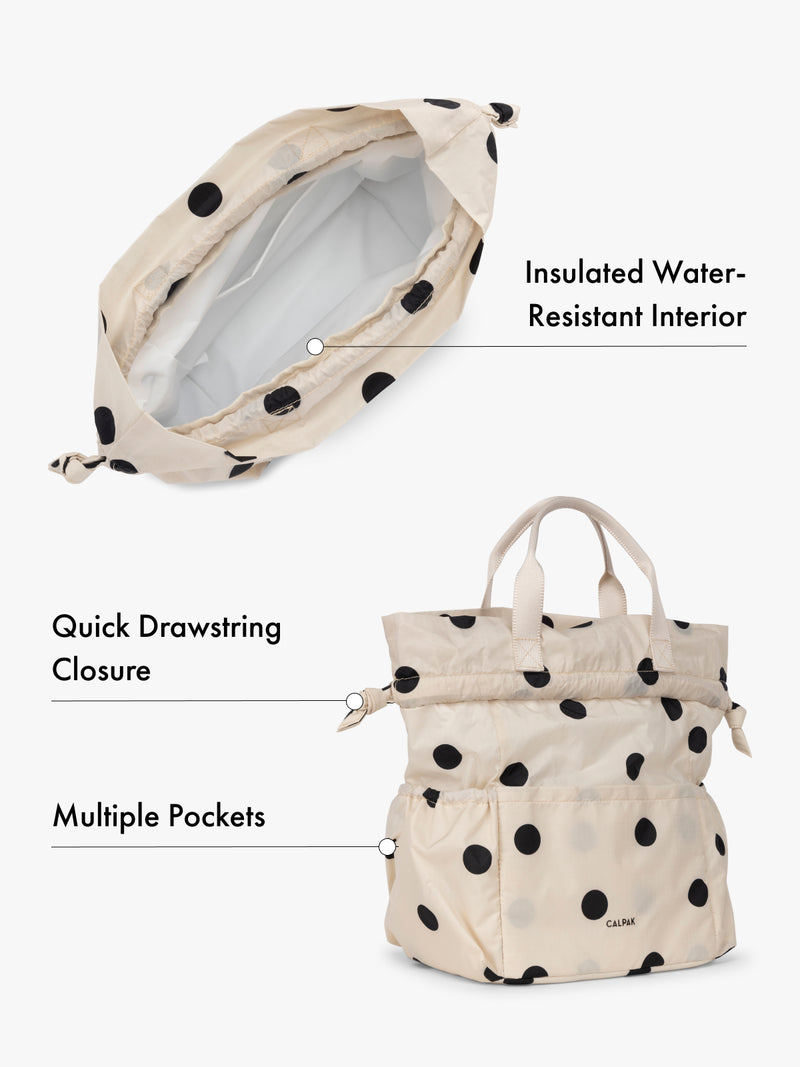 Water resistant interior CALPAK insulated lunch bag with drawstring closure and multiple pockets in beige with black polka dots with features highlighted on white background